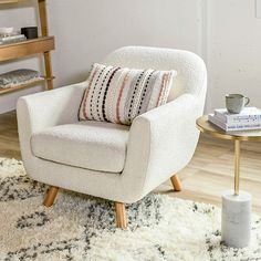 a white chair sitting on top of a rug next to a table with a cup