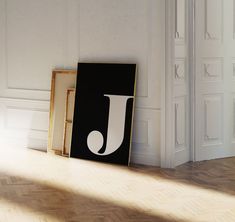 a black and white photo sitting on top of a hard wood floor next to a framed letter j