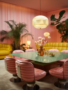 a dining room with pink and yellow chairs, a green table and couches in the background