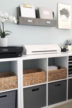 a white shelf with some baskets on top of it next to a printer and other office supplies