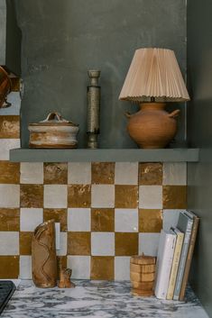 there is a lamp and some books on the shelf in this room with checkered tile