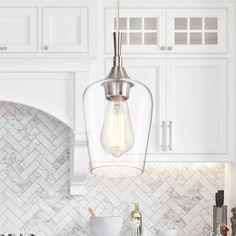 a kitchen with marble counter tops and white cabinets, an island light hanging from the ceiling