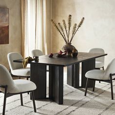 a dining room table with white chairs and a vase filled with flowers on top of it