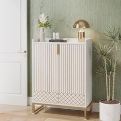 a white cabinet sitting next to a potted plant