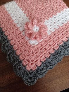 a crocheted blanket with a bow on it sitting on top of a wooden table