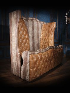 an old leather couch sitting on top of a hard wood floor next to a blue wall