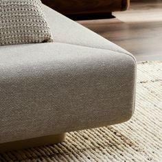 a close up view of a beige couch on a wooden floor in a living room