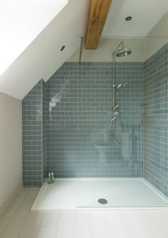 a walk in shower sitting next to a white tiled wall and wooden beam on the ceiling