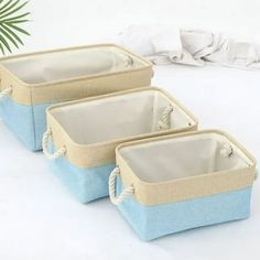 three blue and beige baskets sitting next to each other on a white tablecloth covered surface