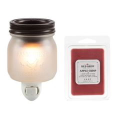 a mason jar light next to an apple crispy wax candle in a package on a white background