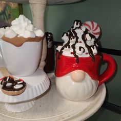 two mugs filled with hot chocolate and marshmallows on a plate next to each other