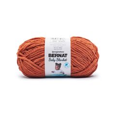 bernat baby blanket yarn in orange, on a white background with the label above it