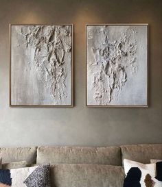 two paintings hang on the wall above a couch in a living room with neutral colors