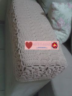 there is a crocheted blanket on top of a couch with pillows in the background