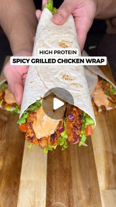 a person holding a burrito on top of a wooden cutting board with the words spicy grilled chicken wrap