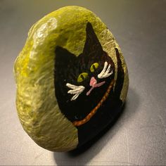 a painted rock with a black cat on it