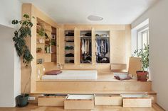 a bed sitting on top of a wooden floor next to a plant in a pot