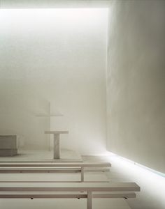 an empty room with benches and a cross