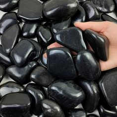 a hand is holding some black rocks