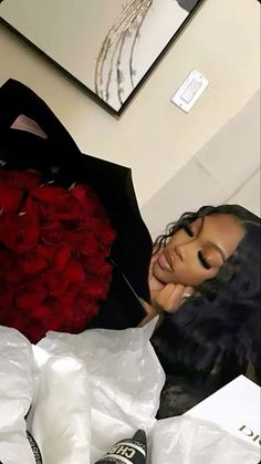 a woman laying on top of a bed next to a bouquet of roses and an umbrella