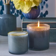 two candles sitting on top of a table next to a vase with flowers in it