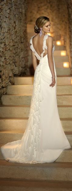 a woman in a white wedding dress standing on stairs with her back to the camera