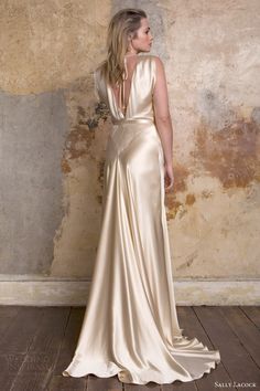 a woman in a gold dress standing against a wall with her back to the camera