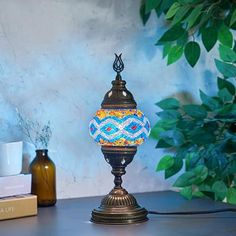 a lamp sitting on top of a wooden table next to a book and vases