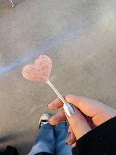 a person holding a heart shaped lollipop on a stick in front of them