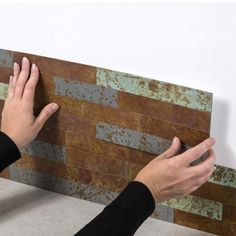 two hands reaching up against a wall with rusted metal tiles on the bottom and sides