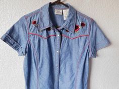 "Blue denim cowgirl short sleeve blouse Red roses engraved pearl snap buttons Red stitches front and back - see photos Condition - a snap button on top on collar missing as shown in photo. Other than that, condition is great Dimension - shoulder 15\" bust 20\" sleeve 7\" length 26\"" Fitted Country Style Short Sleeve Tops, Western Short Sleeve Tops With Button Closure, Western Style Spring Tops With Buttons, Fitted Embroidered Top For Rodeo, Spring Embroidered Tops For Rodeo, Western Style Embroidered Summer Tops, Embroidered Western Tops For Summer, Short Sleeve Tops For Spring Rodeo, Western Short Sleeve Tops For Spring