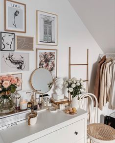 a white dresser topped with lots of pictures and flowers next to a wall mounted mirror