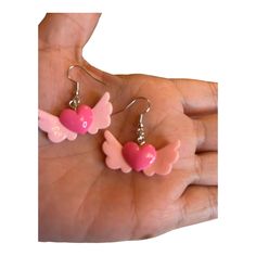 Fly into a world of whimsy with our Winged Heart Earrings! These 1.25" x 0.5" delights are crafted from durable hard plastic, featuring enchanting light pink wings cradling a sizzling hot pink heart at the center. Let your style take flight as these earrings add a touch of playfulness to any outfit. With a design that's as light as the wings themselves, you'll be fluttering through your day with a dash of charm. Embrace the magic of our Winged Heart Earrings – because who says your accessories c Pink Novelty Dangle Jewelry, Whimsical Pink Earrings For Gift, Pink Pierced Earrings As Gift, Plastic Heart Beads Jewelry For Gifts, Pink Double Heart Pierced Jewelry, Pink Heart Beads Dangle Jewelry, Pink Novelty Earrings, Pink Whimsical Pierced Earrings, Pink Heart Earrings With Ear Wire For Valentine's Day