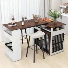 a kitchen table with two stools next to it and a wine bottle on the counter