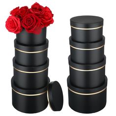 a stack of black and gold boxes with red roses in them on a white background