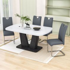 a dining room table with grey chairs and a white rug on the floor in front of it