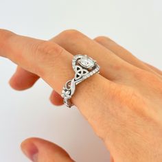 a woman's hand with a diamond ring on her left hand and an intricate knot around the band