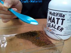 a person holding a spoon over a container of dirt next to a bottle of multiflia mat sealer