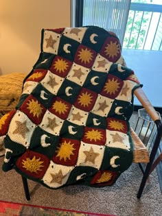 a crocheted blanket sitting on top of a chair in front of a window