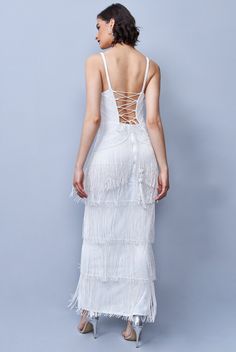 the back of a woman wearing a white dress with fringes on it and an open back