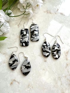 Black and grey polymer clay dangle earrings. Accented with silver leaf and sealed with resin. Hardware is silver plated. This item is handmade and may vary slightly in appearance. Silver Resin Drop Earrings, Nickel-free Silver Resin Earrings, Silver Resin Earrings As A Gift, Silver Resin Earrings For Gift, Minimalist Silver Resin Jewelry, Silver Polymer Clay Earrings For Gift, Silver Dangle Earrings In Polymer Clay, Handmade Silver Polymer Clay Jewelry, Gray Ear Wire Earrings For Gift