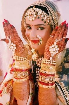 a woman with her hands covered in henna and jewelry, posing for the camera