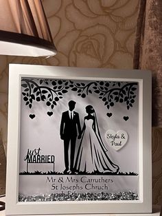 a wedding cake topper with a bride and groom under a tree in the background