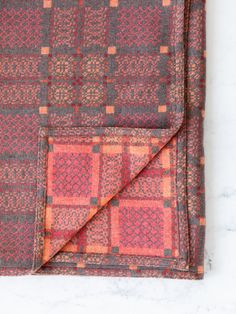 an orange and grey plaid pocket square on a marble surface with a red, black, and white checkerboard pattern