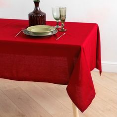 a red table cloth with silverware and wine glasses on it