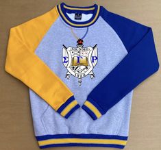 a blue and yellow sweatshirt with an emblem on the front, sitting on a table