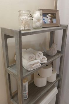 there is a shelf with towels and toilet paper on it next to a framed photo