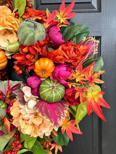 a wreath with flowers and pumpkins on the front door