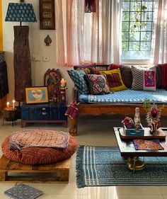 a living room filled with lots of furniture next to a window covered in sheer curtains