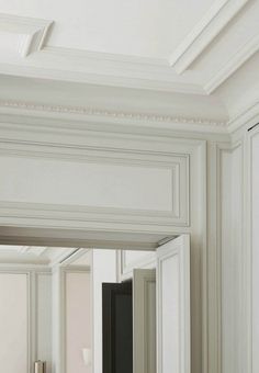 an empty bathroom with white walls and trimmings on the ceiling, along with a large mirror